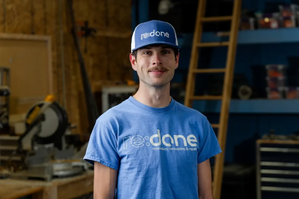 Young man smiling at the camera, giving a thumbs up while working on his laptop.